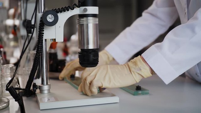 assistant puts slide to microscope to check product quality