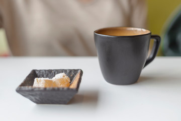 Young woman with curly hair is drinking coffee in a cafe