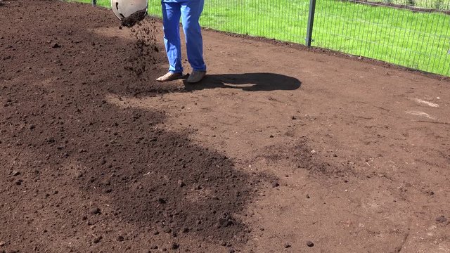 Skilled landscaper pour fertile earth to enrich soil for lawn sow. Static