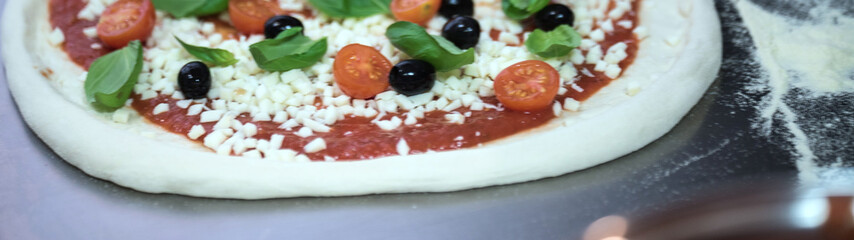 Cook in the kitchen putting the ingredients on the pizza. Pizza food concept.