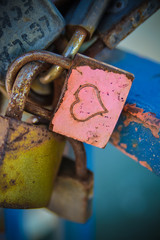 A rusty red love lock with a heart