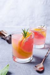 Grapefruit drink with rosemary on grey board.