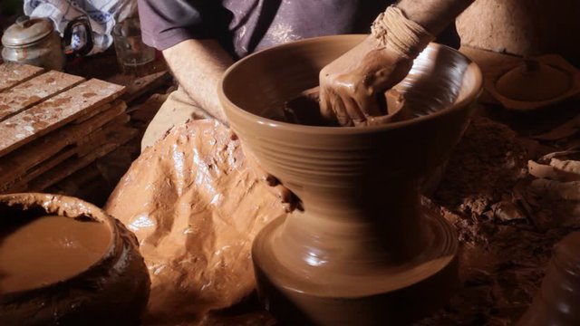 Moroccan craftsman is creating a specific shape of pottery 