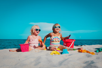 cute little girls play with sand on beach