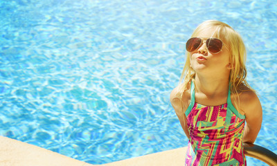 Children blond girl in swimming pool. Summer vacations.