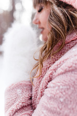 A beautiful pretty young girl with curly hair and a snow-white smile in a pink fur coat is walking...