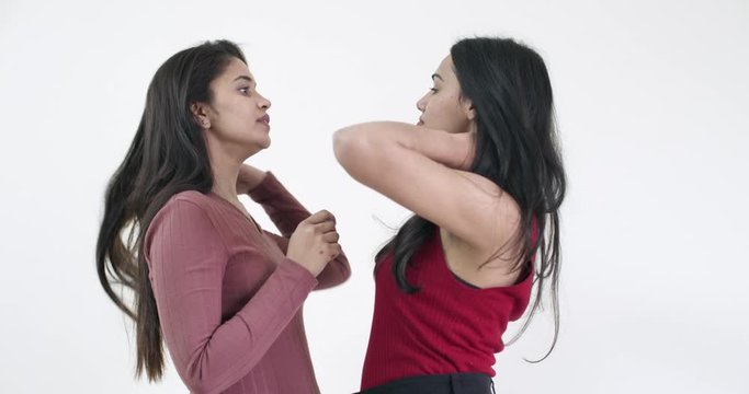 Two pretty ladies touch and caress each other with tender romantic embrace, dance and discuss sweet nothings face to face, mid-shot on white studio background isolated slow-motion handheld 60fps