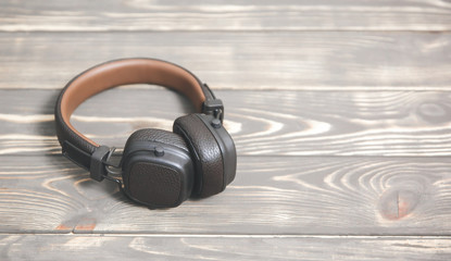 Fototapeta na wymiar Brown leather headphones on vintage wooden background. Modern music concept.