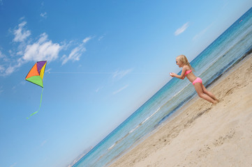 Little happy girl playing with flying kite. Summer vacation concept