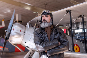 Obraz na płótnie Canvas Middle-aged pilot, posing in front of a classic plane