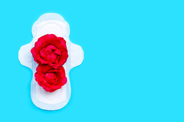 Obraz na płótnie Canvas White sanitary napkin with red roses on blue background.