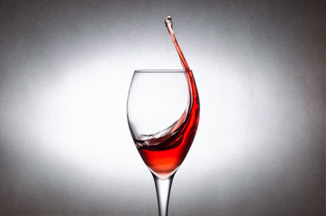 Glass with splashes, drops of red wine on a white background. Freezing liquids in motion