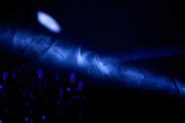 Blue beam of the stage spotlight in the dark, through the smoke
