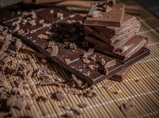 Chocolate tablet of different flavors placed on plate with pieces of chocolate and cinnamon
