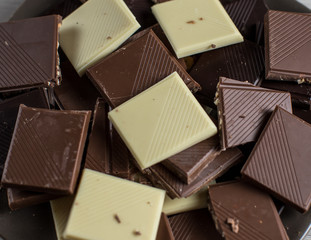 Chocolate tablet of different flavors placed on plate with pieces of chocolate and cinnamon