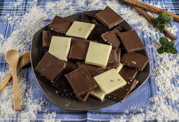 Chocolate tablet of different flavors placed on plate with pieces of chocolate and cinnamon