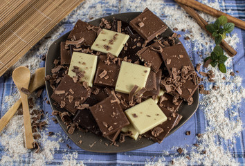 Chocolate tablet of different flavors placed on plate with pieces of chocolate and cinnamon