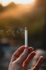 Person holding a lit cigarette in his hand.