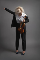 Fototapeta premium Young woman violinist in a black male suit with a violin putting on her jacket