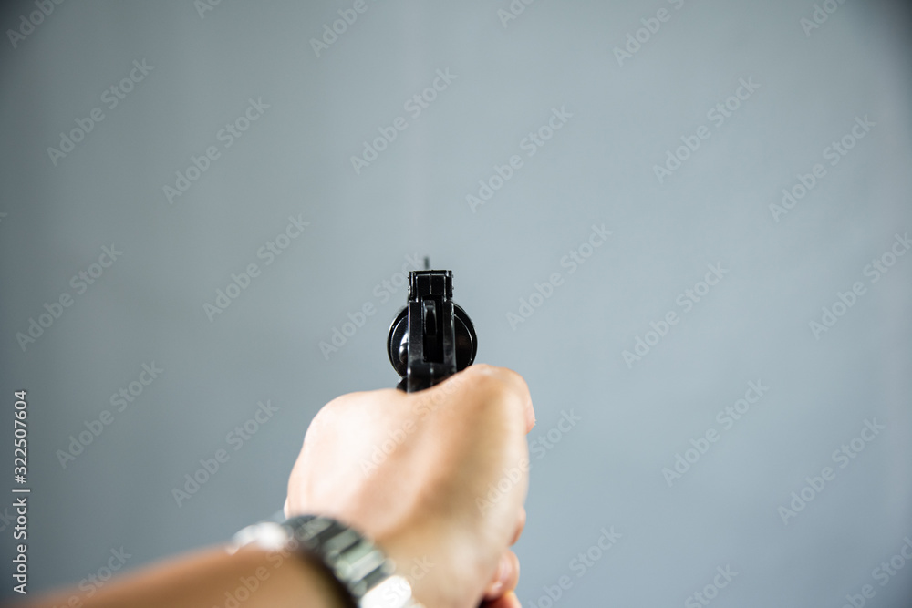 Wall mural gun in hand on grey background.