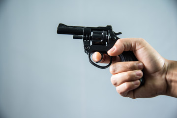 Gun in hand on grey background.