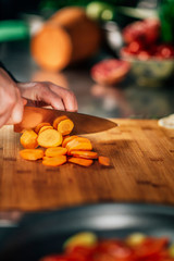 Preparing Vegan Meal -  Chef Cutting Carrot on Wooden Cutting Board