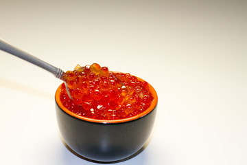 red caviar in a saucer with a spoon on a light table. the concept of a delicious Breakfast, buffet and snack. seafood dish. the view from the top. space for text.