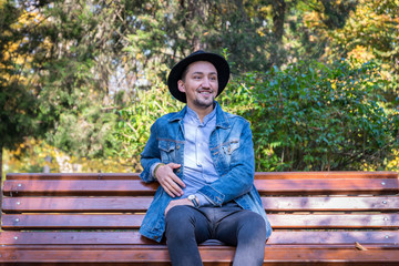 Handsome young man looking at the camera. Portrait of laughing confident and successful young man with a denim jacket and blue shirt outside. Happy guy smiling