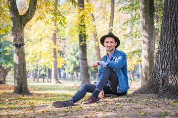Fototapeta premium Handsome young man looking at the camera. Portrait of a confident and successful young man with a denim jacket and blue shirt outside. Happy guy smiling