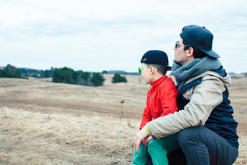 young father with his son having fun outside in spring field, happy family smiling, lifestyle people making selfie wearing sunglasses