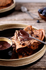 Chocolate Crepes with chocolate sauce and blueberry on vintage wooden table. Selective focus