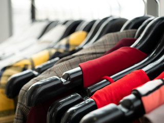 Various fashion woman clothes included luxury red dress, modern brown suit, classic white blazer, elegance coat and formal shirt costume closet hanging for stylish select in retail shop brand store