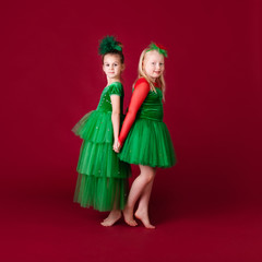 Beautiful little girl princesses dancing in luxury green dress isolated on red background. Carnival party with costumes