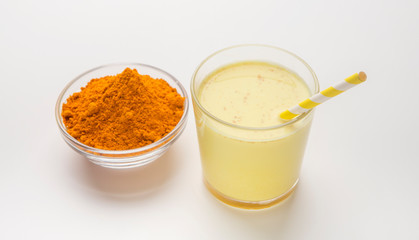 Golden milk with turmeric in a glass on white background