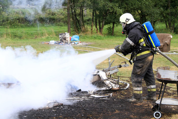 Wohnwagen-Brand - Feuerwehrmann löscht den Brand