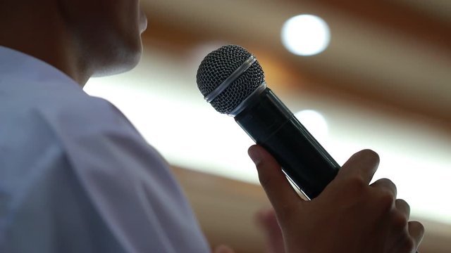 Speaker in Seminar Conference Concept: Rear side Smart businessman speech and speaking with microphone talking in auditorium room. Event light convention hall Background. Business Presentation speak