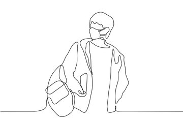 A man in a medical mask in an unbuttoned jacket and backpack holds something in his hands and looks away. Black outline of a man before or after a trip