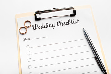 Paper planner and wedding rings on white table