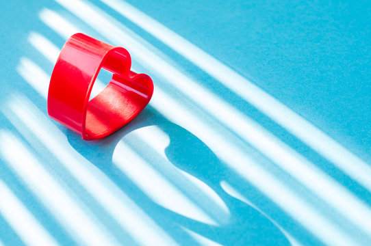 Heart shaped red cookie cutter on blue background.