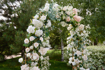Beautiful wedding arch decorated with white and pink flowers in garden outdoors, copy space. Wedding setup. Place for ceremony. Floral composition