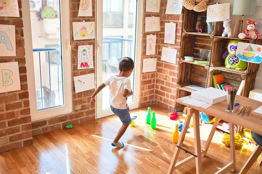 Beautiful african american toddler playing bowling at kindergarten