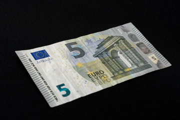 Detail of 5 euro banknote with anti-counterfeiting holograms, Selective focus, black background, one banknote.
