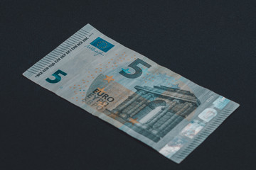 Detail of 5 euro banknote with anti-counterfeiting holograms, Selective focus, black background, one banknote.