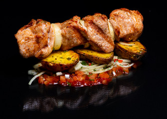 Barbecue meat dish and baked potatoes with vegetables..