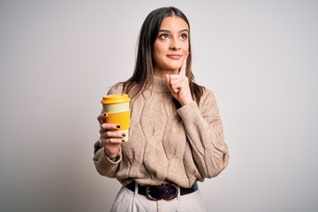 Young beautiful brunette woman drinking glass of coffee over isolated white background serious face...