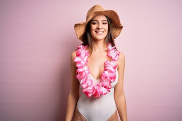 Young beautiful brunette woman on vacation wearing swimsuit and Hawaiian flowers lei with a happy and cool smile on face. Lucky person.