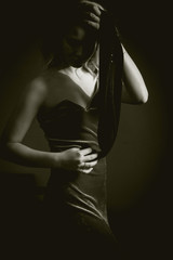 black and white Studio portrait of blonde on a dark background in a dark dress he closes his eyes with a black ribbon