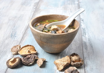 Japanese miso soup with fresh tuna, dried seaweed, tofu, shiitake dried mushrooms in a wooden bowl on the wooden background