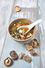 Japanese miso soup with fresh tuna, dried seaweed, tofu, shiitake dried mushrooms in a wooden bowl on the wooden background