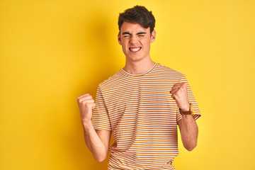 Teenager boy wearing yellow t-shirt over isolated background very happy and excited doing winner...